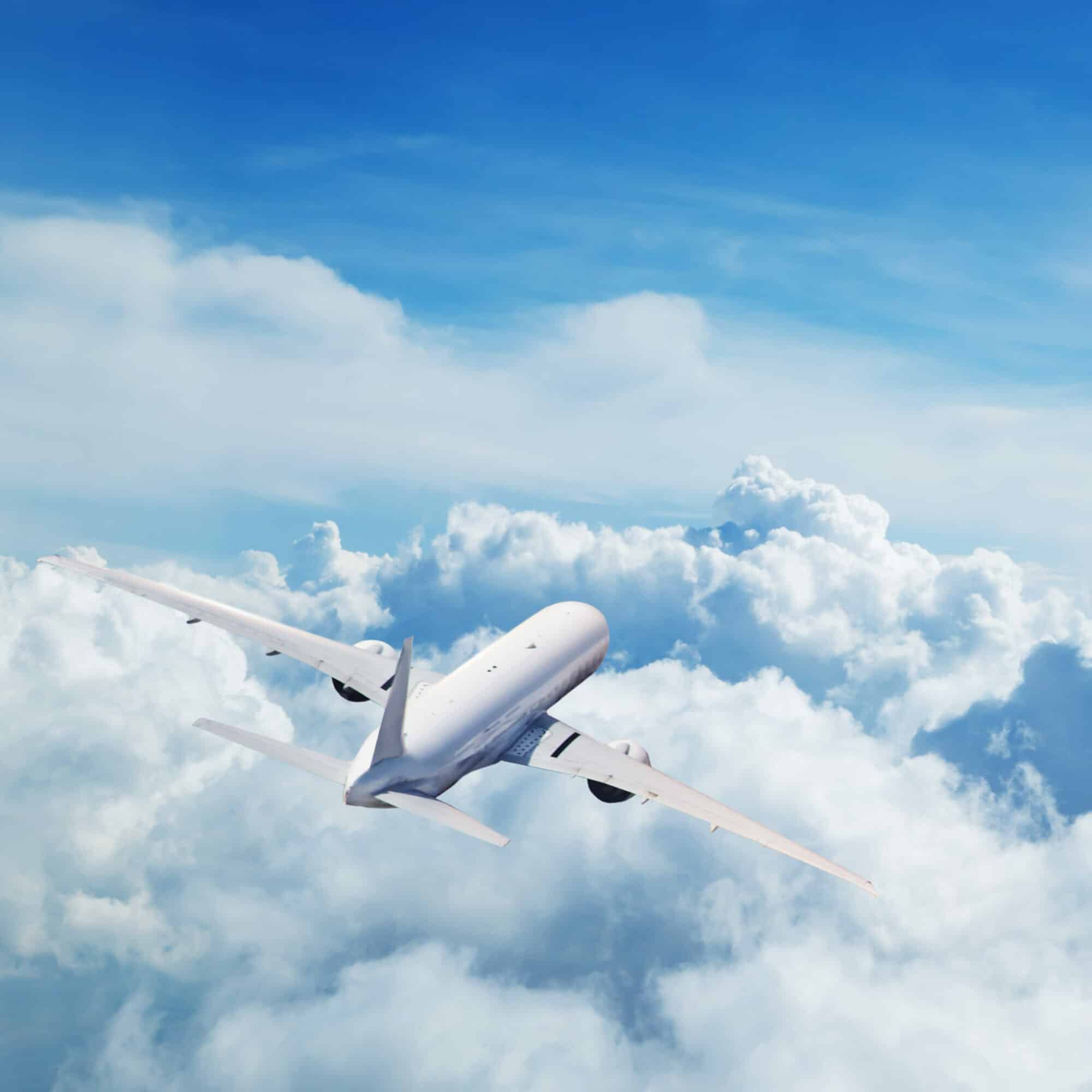Back view of commercial airplane flying above clouds. Copyspace for text